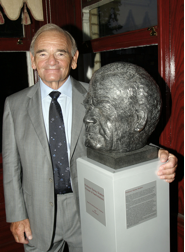 Man in suit beside a bust on a plinth